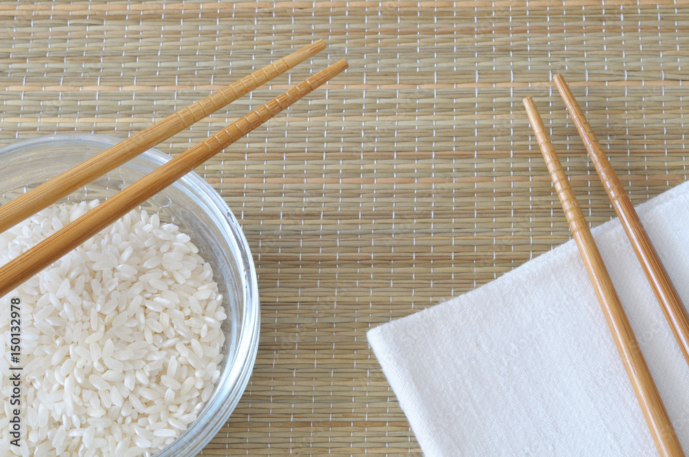 White rice with a chopsticks and napkin, on a bamboo placemat, top view White rice with a chopsticks and napkin, on a bamboo placemat, top view