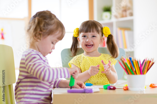 smiling kids painting at home or day care center