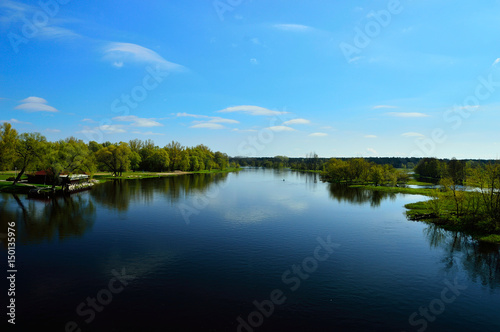Fototapeta Naklejka Na Ścianę i Meble -  Rzeka i brzeg z trawą z niebem z chmurami.