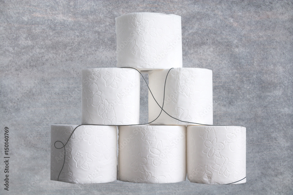 Stack of toilet paper rolls on wooden table against white brick wall. Copy space. Stack of toilet paper rolls on wooden table against white brick wall. Copy space.