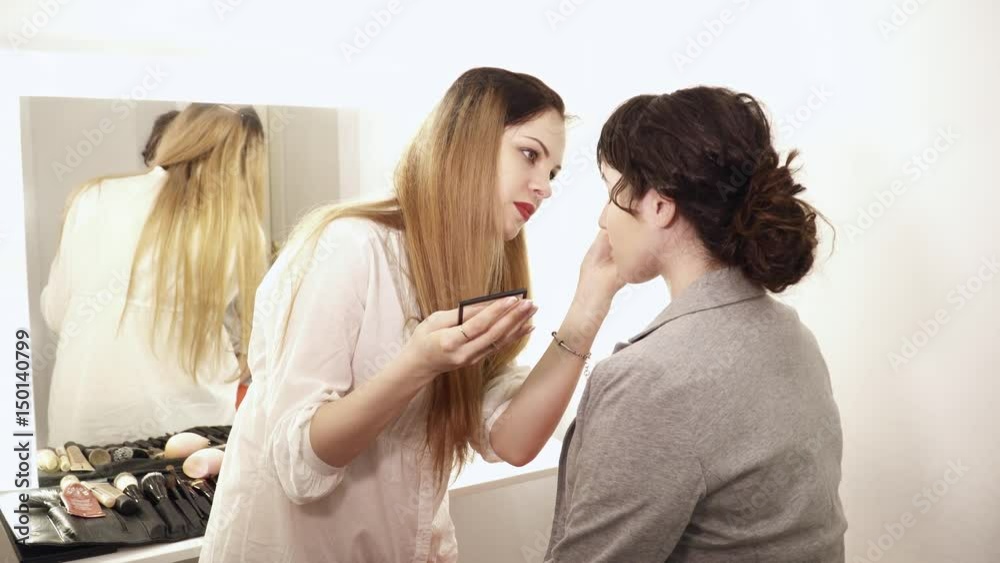 Makeup artist applying the eye shadows for a young woman Makeup artist applying the eye shadows for a young woman