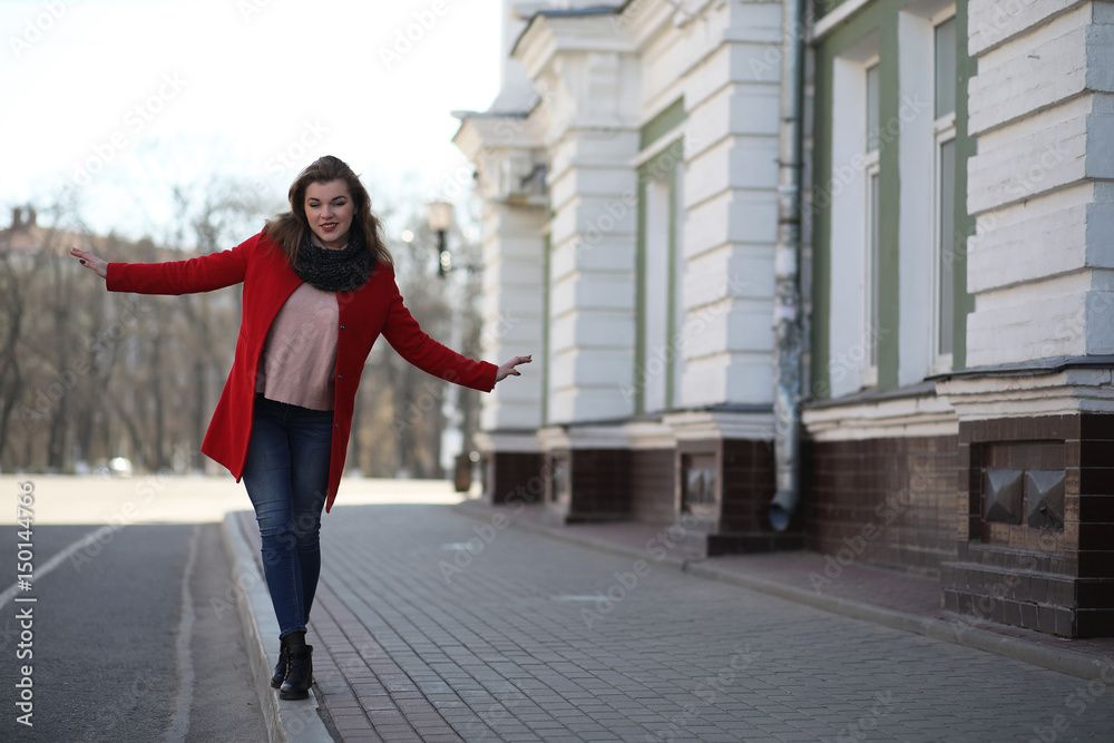 Obraz premium Pretty girl on a walk in red coat in the city