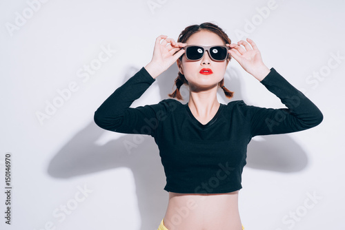 Young asian girl doing emotion. Dressed in a black shirt and yellow skirt, glasses and bright lips,trendy clothes. Warm color. White background, not isolated