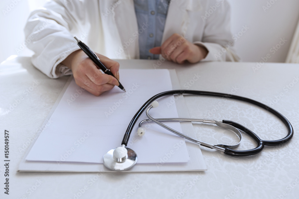 Doctor and patient are discussing about diagnosis, hands at the table. Female doctor taking notes. Doctor and patient are discussing about diagnosis, hands at the table. Female doctor taking notes.