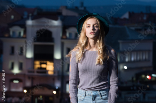 woman with hat in profile against night city background