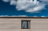 Window on mobile home caravan with blue sky cloudy background