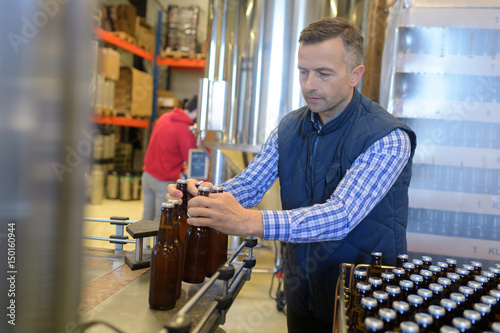 Factory operative packing bottles from end of production line