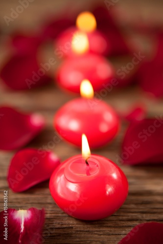 Red wax candles surrounded with rose petals