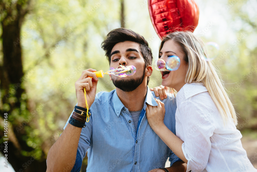 Fototapeta premium Beautiful young couple blowing soap bubbles and smiling