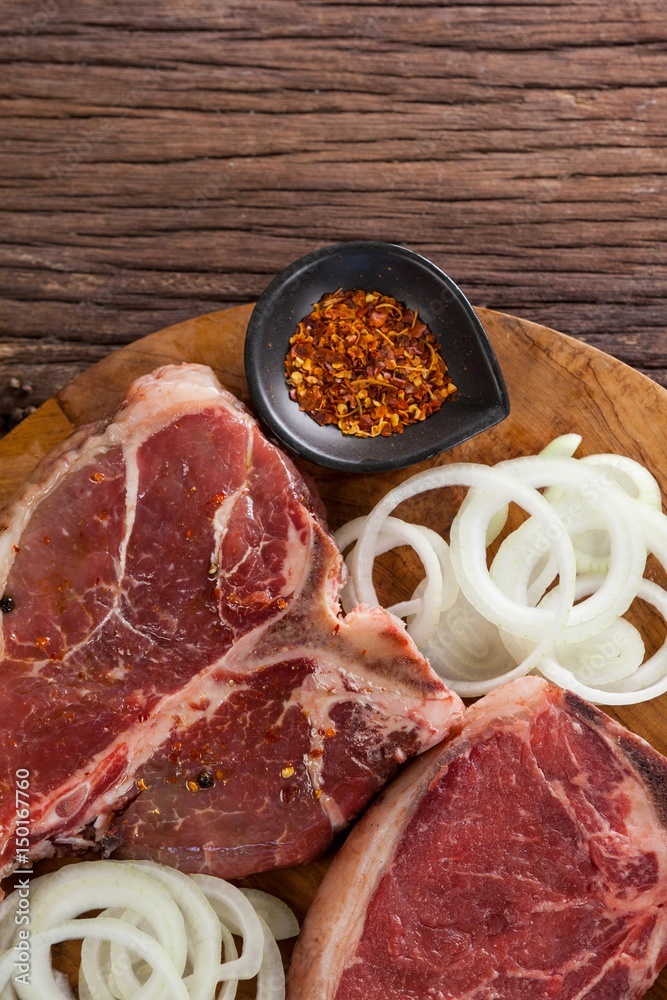 Blade chop, onions and spices on wooden round tray Blade chop, onions and spices on wooden round tray