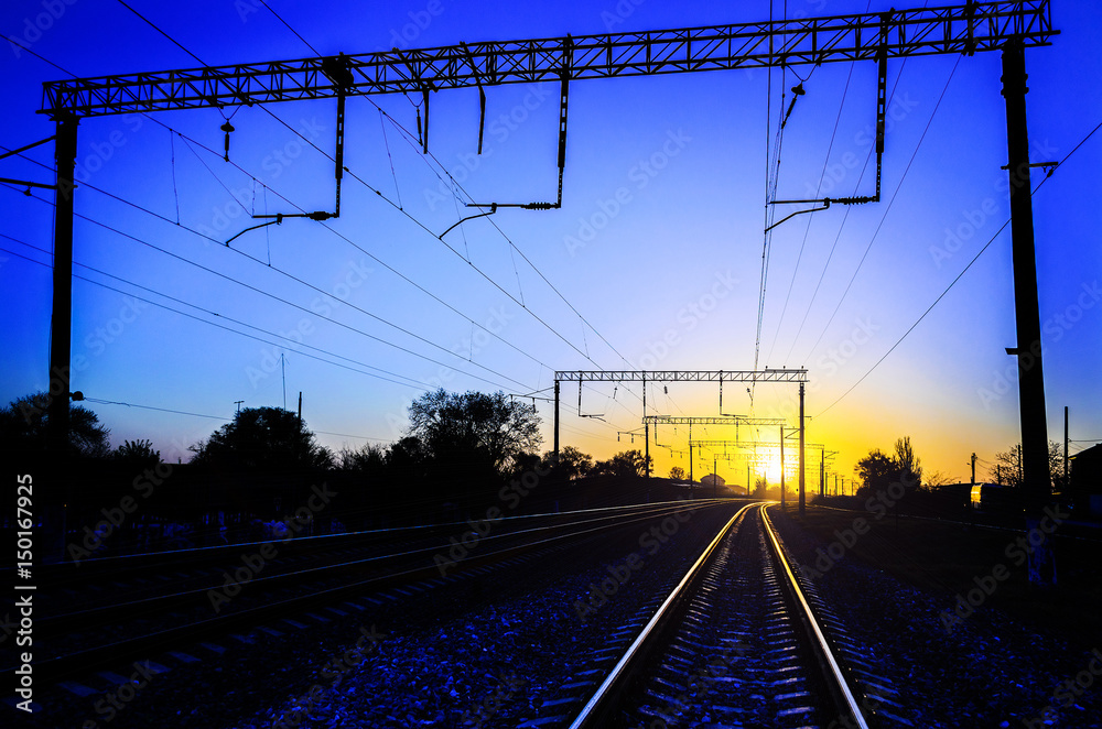 Railway - Railroad at sunset with sun, Rails and electric lines in yellow light