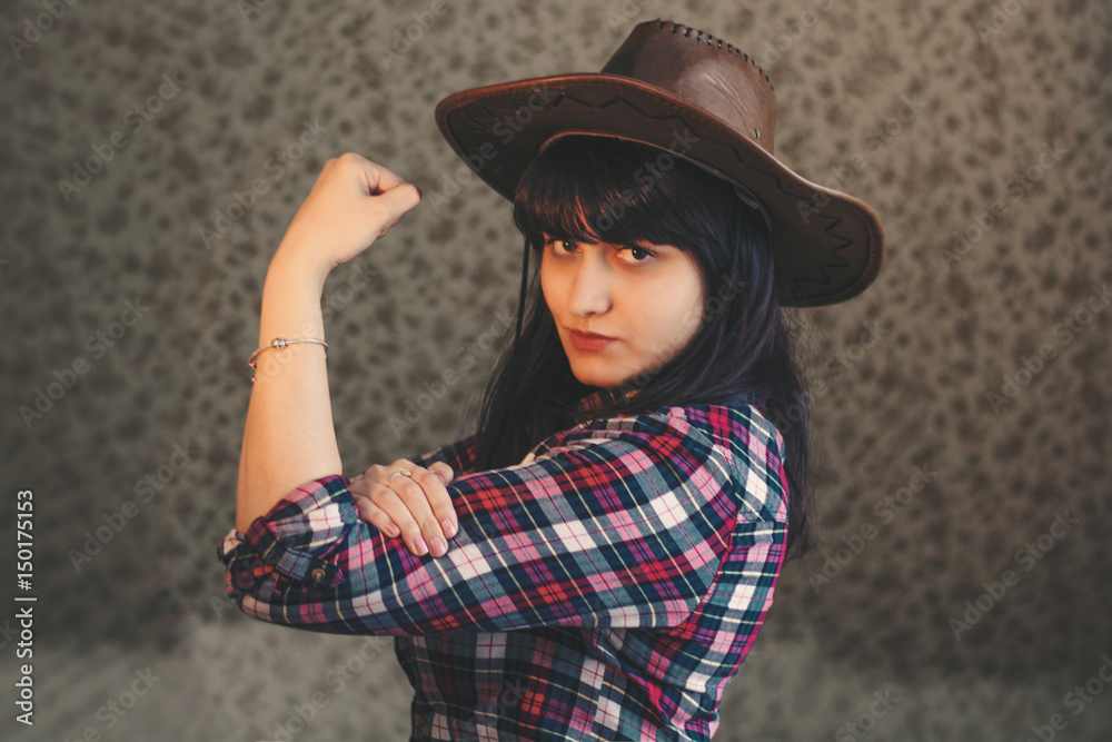 retro toned photo of young girl in a cowboy hat shows her biceps.