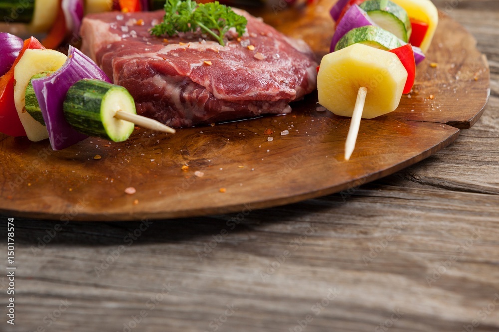 Sirloin chop and skewered vegetables on wooden board