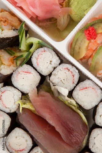 Assorted sushi set served in white box against white background