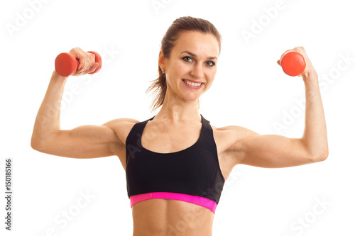 a cheerful athletic girl in black top keeps dumbbells and shows muscle
