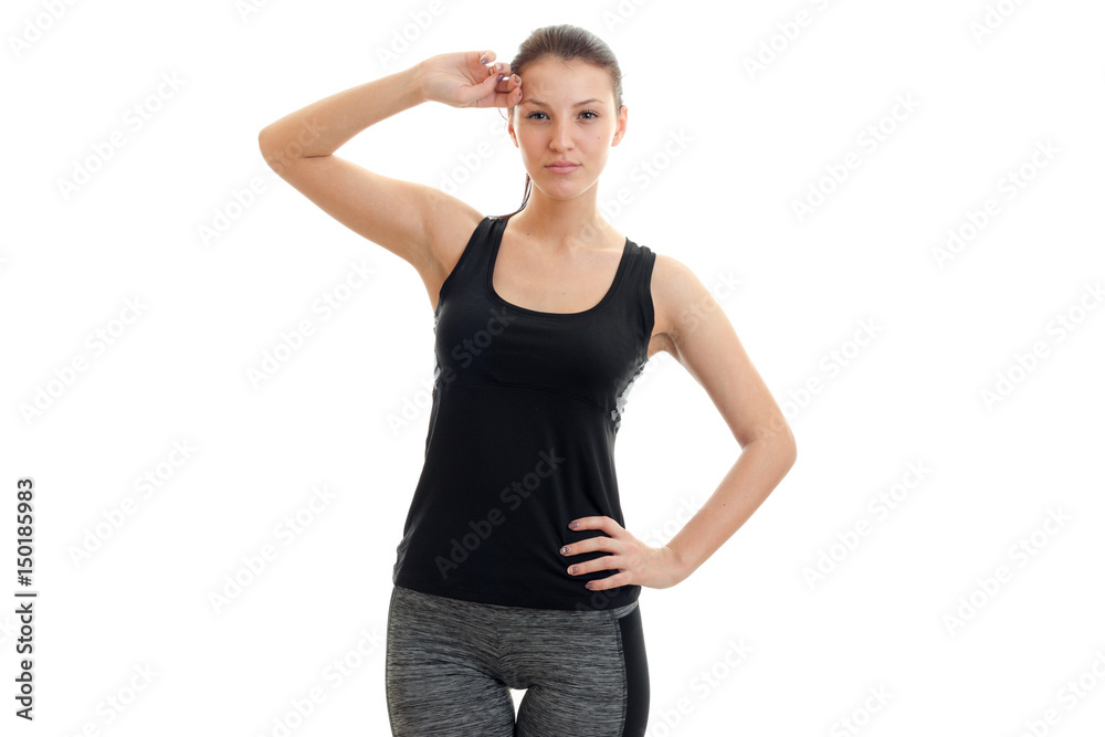 a young athletic girl in black suit keeps one hand on the side and the second near the head a young athletic girl in black suit keeps one hand on the side and the second near the head