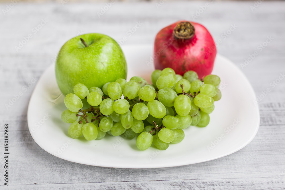 Fresh apples, grapes and pomegranate on the table. Ecological wooden background. Fresh apples, grapes and pomegranate on the table. Ecological wooden background.