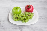 Fresh apples, grapes and pomegranate on the table. Ecological wooden background.
