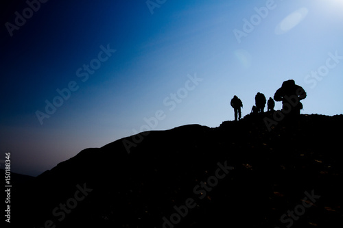 Silhouette of Men Hiking a Mountain