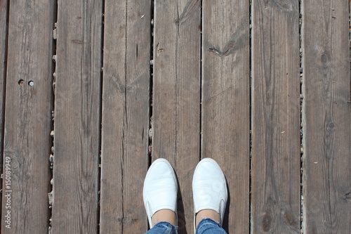 Old wooden floor and feet in white shoes