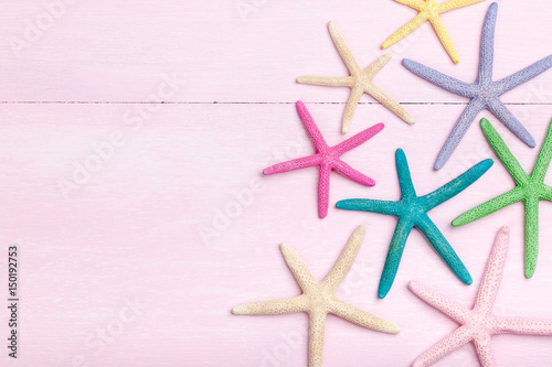 Colorful starfishes on pink wooden background