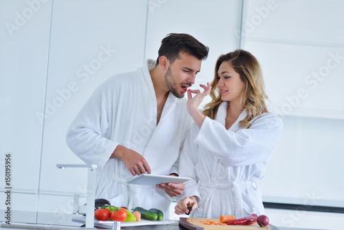 Couple in home kitchen using electronic tablet photo