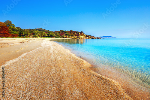 Beautiful beach line with yellow sand, small pebble and turquoise water of Aegean sea. Sunny spring day scene. Proti ammoudia beach near Olympiada town summer resort, Kavala region, Greece. photo