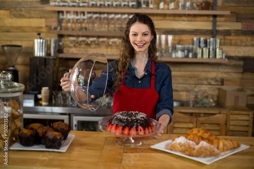 Portrait of waitress serving cake at counter in café