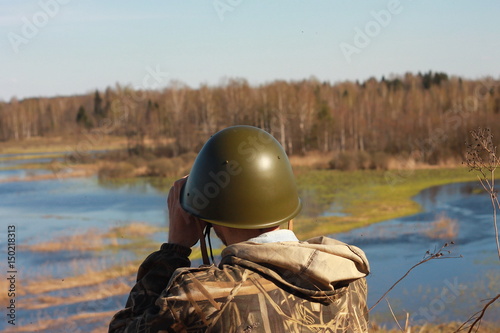 Солдат с биноклем на берегу реки