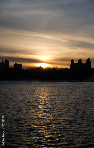 Sunset and silhouette buildings over lake
