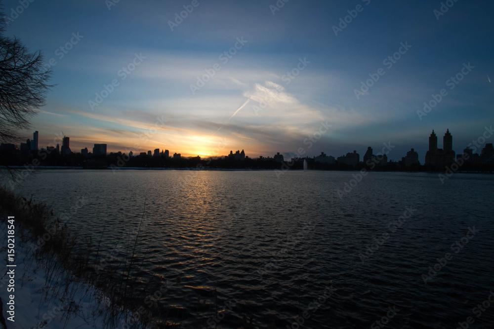 Blurred sunset over buildings and lake in New York