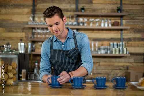 Waiter preparing cup of coffee at counter