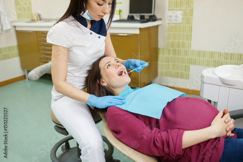 Young dentist with pregnant patient