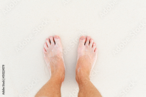 Male`s foot on sand © byrdyak