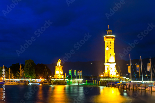 Lighthouse and a lion statue gurading an entrance to the port of Lindau during night, Germany. photo