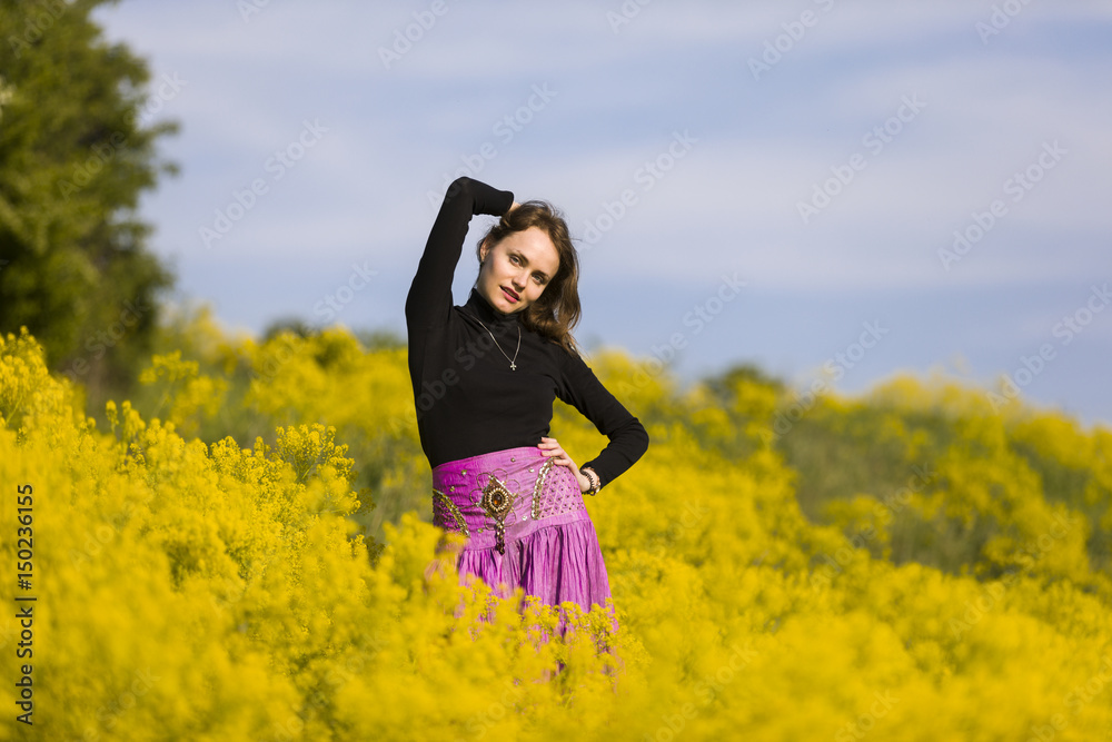 Young woman standing in a field of yellow flowers Young woman standing in a field of yellow flowers