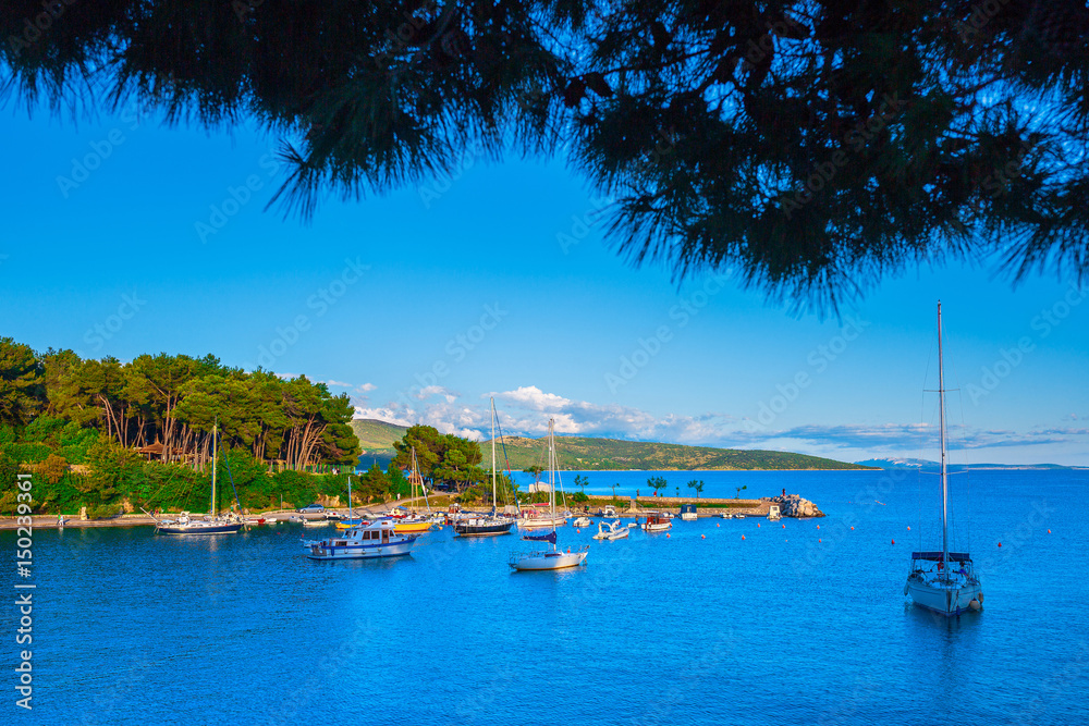 Wonderful romantic summer landscape panorama coastline sea. Boats and yachts in harbor at cristal clear azure water. Green trees at the edge of the coast.