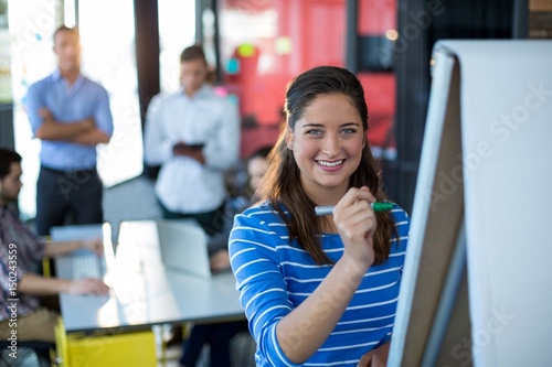 Portrait of businesswoman writing on flip chart