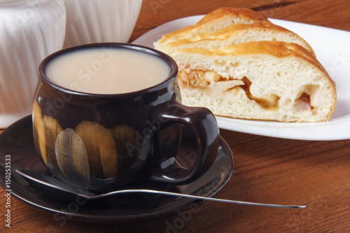 Fresh homemade apple pie and tea with milk on a wooden background