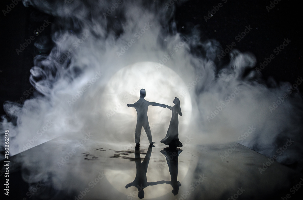 Silhouettes of toy couple dancing under the Moon at night. Figures of man and woman in love dancing at moonlight Silhouettes of toy couple dancing under the Moon at night. Figures of man and woman in love dancing at moonlight