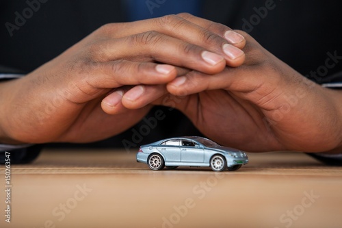 Businessman protecting toy car with hands