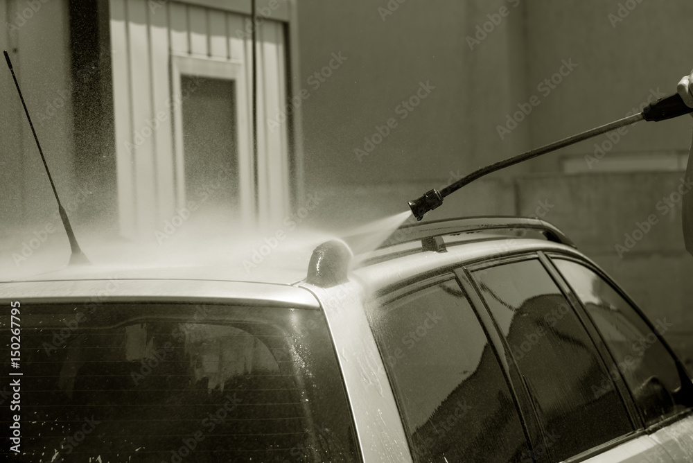 Worker in auto service is washing a luxury car Worker in auto service is washing a luxury car