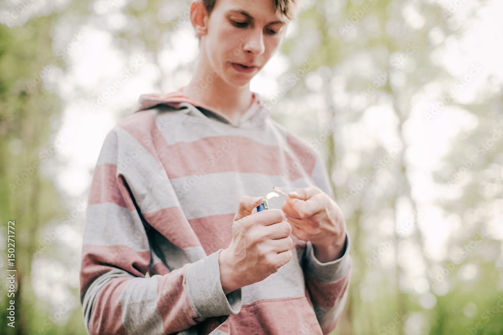 Teen man burning a wood chip at campsite. Teen man burning a wood chip at campsite.