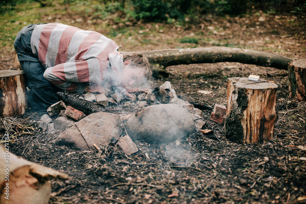 Fototapeta premium Camper blowing into campfire to get fire started.