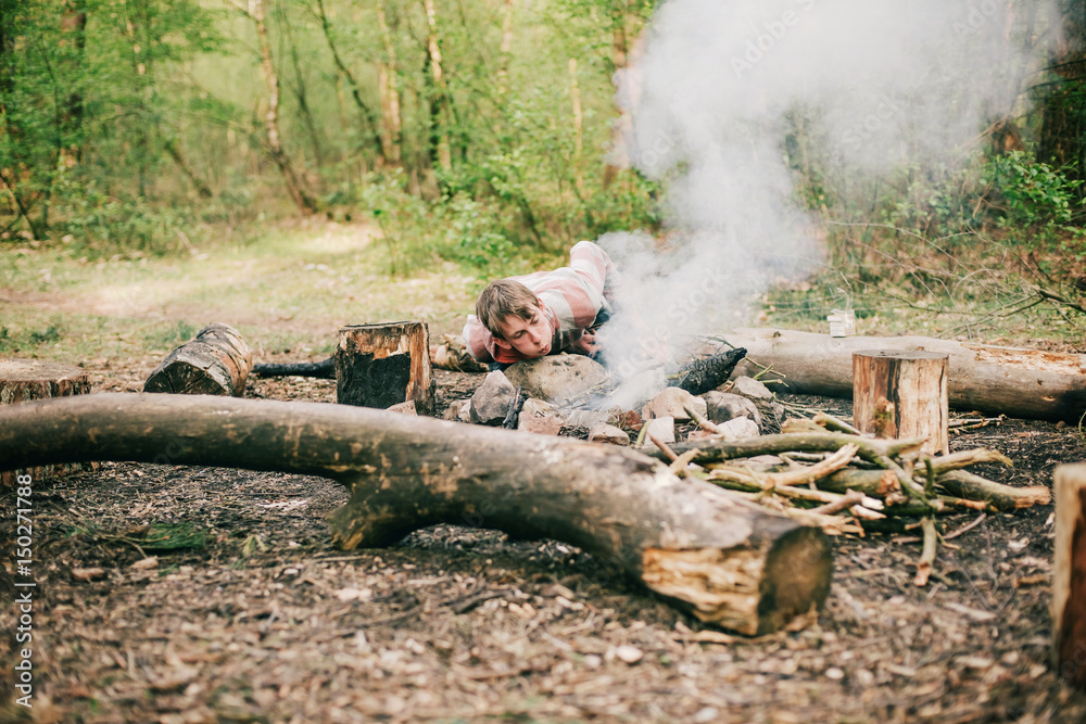 Camper blowing into campfire to get fire started. Camper blowing into campfire to get fire started.