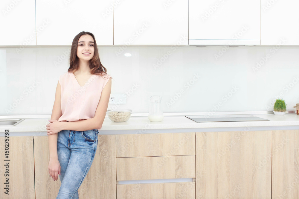 Serious attitude. Young smiling lady standing in a kitchen. Serious attitude. Young smiling lady standing in a kitchen.