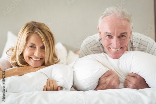 Portrait of happy senior couple lying on bed 