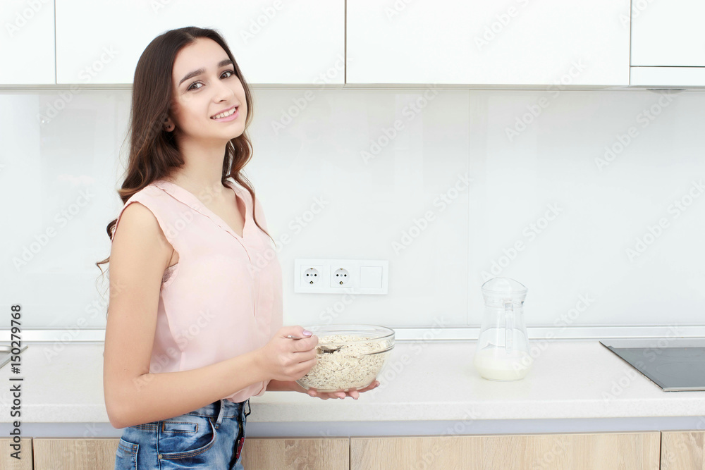 Healthy breakfast . Young beautiful cheerful woman putting cereal in a bowl while sitting on the worktop and smiling. Healthy breakfast . Young beautiful cheerful woman putting cereal in a bowl while sitting on the worktop and smiling.
