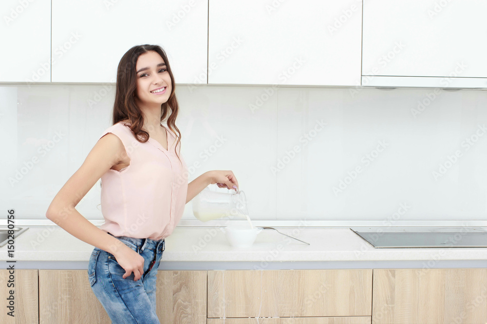 Woman pouring milk on plate with cereal muslin at kitchen Woman pouring milk on plate with cereal muslin at kitchen