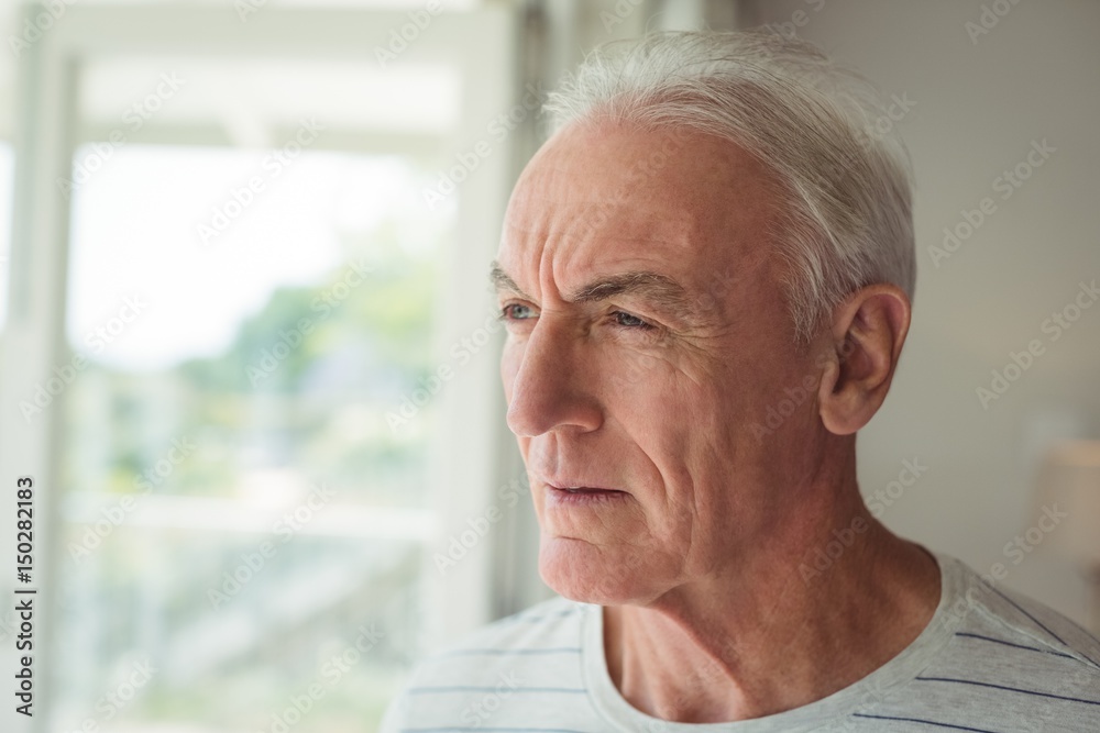 Thoughtful senior man standing next to window Thoughtful senior man standing next to window